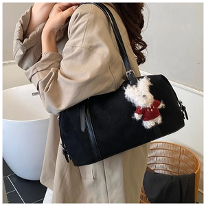 Close-up of black suede tote bag with leather strap and a cute white rabbit pendant