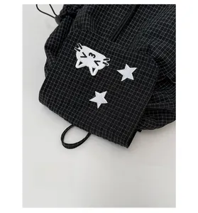 Detail of cute cat and star embroidery on black checkered drawstring backpack fabric