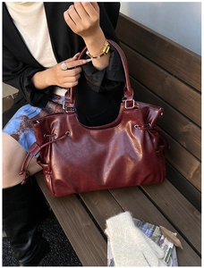 Deep burgundy oil-wax leather tote bag with side drawstring details on a street style setting