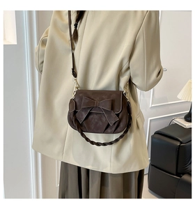 Detail of dark brown frosted underarm bag with bow decoration and woven handle