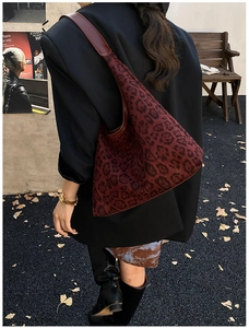 Detailed texture of burgundy leopard print tote bag on shoulder in street style setting
