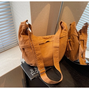 Gros plan d'un sac hobo en toile jaune en forme de croissant avec détail de glands