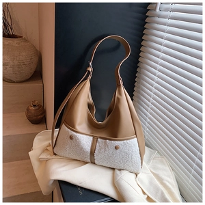 Detail of hobo bag showing khaki leather texture and white plush fleece front pocket