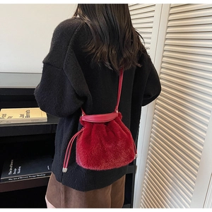 Detailed close-up of a red faux fur bucket bag with leather drawstring and soft texture