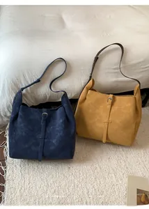 Détail de sacs fourre-tout bleus et jaunes montrant la texture en cuir mat et la boucle