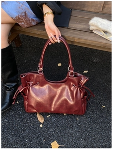 Deep red leather tote bag with vintage texture and drawstring detail in outdoor setting