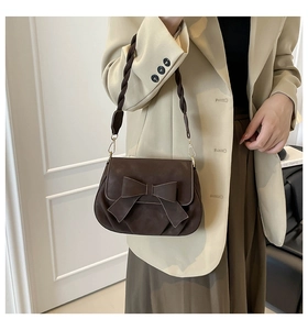 Dettaglio della borsa in PU satinato marrone con grande fiocco e tracolla intrecciata