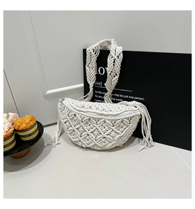 Detail of white woven boho crescent bag showing braided strap and tassel accents