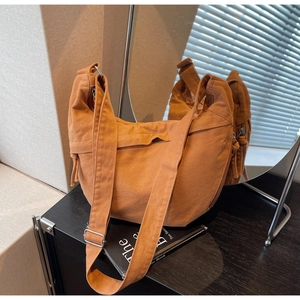 Détail du sac hobo en toile jaune moutarde avec large bandoulière et boucles argentées