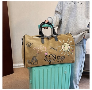 Close-up of khaki canvas travel bag with cartoon graffiti and black leather handles