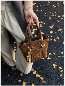 Dettaglio borsa a secchiello in pelle scamosciata leopardata con logo L e ciondolo