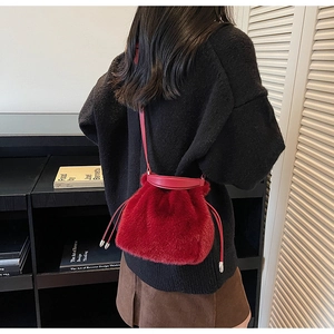 Detail of red faux fur bucket bag featuring a drawstring closure and leather strap