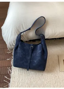 Détail d'un grand cabas bleu foncé en cuir vintage posé sur un tapis douillet