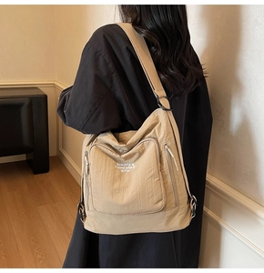 Detail showing the khaki tote bag's front pocket with 'Beautiful is Found' text and texture