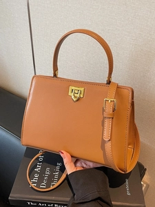 Brown faux leather handbag with gold twist lock shown at a 45-degree angle