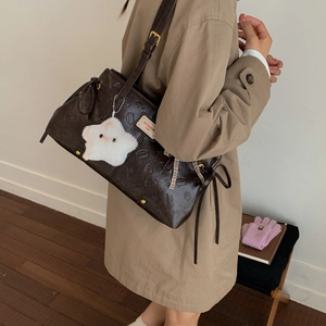 Detail of vintage brown leather bag with embossed cartoon patterns and star plush pendant