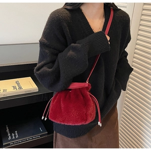 Detail of red plush bucket bag with drawstring closure worn by model for winter style