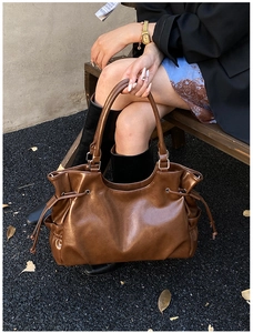 Detail shot of a brown oil wax leather tote bag with drawstring closure and glossy finish