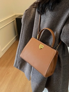 Brown leather crossbody bag with gold hardware worn by model in grey wool coat