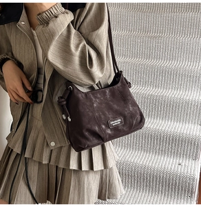 Detail of dark brown matte shoulder bag with vintage texture and knotted strap design