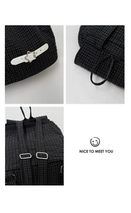Detail of black grid nylon backpack with star buckle, drawstring and metal hardware