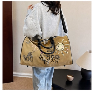 Detail view of khaki canvas travel bag with graffiti prints worn by a model in interior