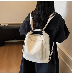 Detailed back view of a multi-pocket cream white nylon backpack worn by a model