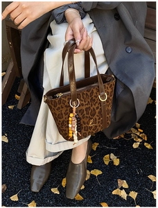Dettaglio borsa vintage leopardata con manici in pelle lucida e ciondolo con perline
