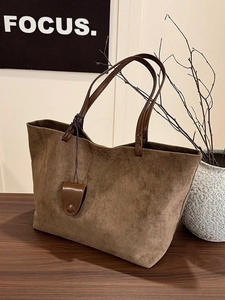 Minimalist large capacity dark brown suede tote bag on a wooden table with leather handles