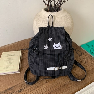 Close-up of black plaid backpack with cute cat embroidery and star-shaped metal buckle