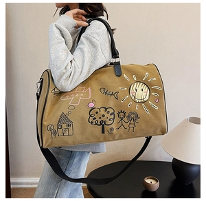 Brown canvas travel bag featuring artistic hand-drawn graffiti and adjustable shoulder strap