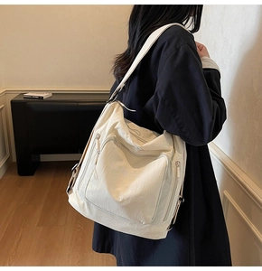 Detail view of cream-white large capacity tote bag featuring multi-zipper pockets