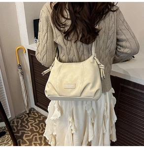 Detail of a beige leather bucket bag featuring a drawstring design for daily commute