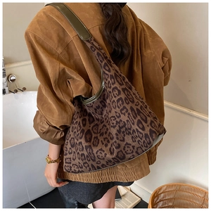 Detail of vintage leopard print tote bag with olive leather trim worn by a model