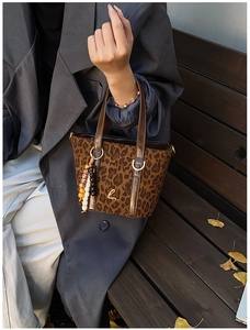 Dettaglio borsa a secchiello leopardata con logo dorato e nappa di perline