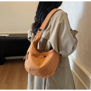 Mannequin portant un sac croissant en toile jaune moutarde avec bandoulière sur un trench beige