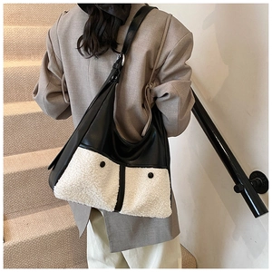 Detail of plush lamb wool and black leather patchwork tote bag shown on a model shoulder