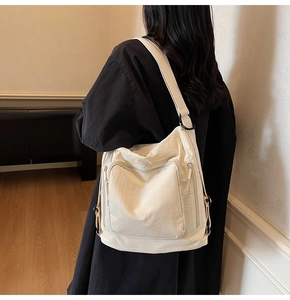 Detail of cream white nylon tote bag with functional zipper pockets and adjustable strap