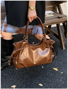 Close-up of dark brown vintage tote bag with drawstring detail and glossy leather texture
