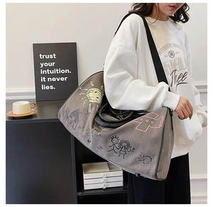 Detailed view of grey canvas travel bag with colorful hand-drawn graffiti on a model