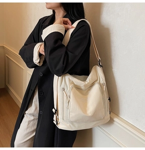 Close-up of a cream waterproof nylon tote bag with multi-pocket design on models shoulder