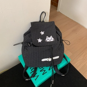 Detail of drawstring plaid backpack with cute cat embroidery and white buckle closure