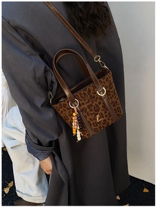 Dettaglio borsa tote leopardata con manici in pelle marrone e logo dorato raffinato