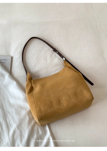 Détail d'un sac bandoulière en daim jaune gingembre avec bandoulière en cuir marron et boucle