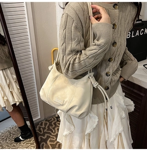 Detail of beige pleated faux leather bucket bag with a knotted shoulder strap design