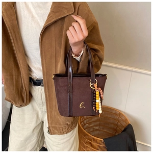 Dettaglio ravvicinato della borsa in pelle scamosciata con logo b e perline in legno