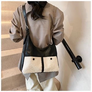 Detail of black leather crossbody bag with white faux fur pockets and adjustable strap