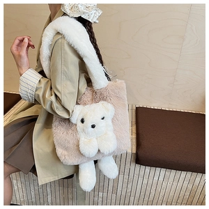 Detail of plush beige tote bag featuring a 3D white teddy bear and wide fuzzy strap