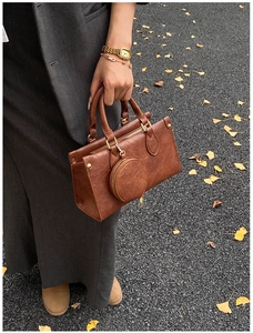 Detailed close-up of a brown retro PU leather handbag with a round coin purse accessory