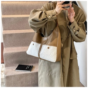 Detail of the brown leather and white faux fur tote bag with decorative snap pockets